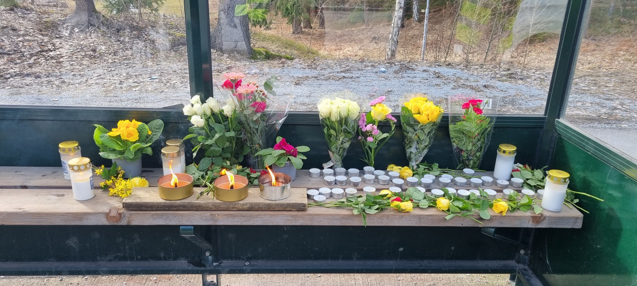 Minnesplats med blommor och ljus vid busshållplats i Tyresö efter våldsdåd nära Tyresö gymnasium